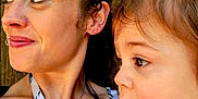 Micah is registered to the contest to win money with this photo: blue_shirt, casual, child, closeup, curly_hair, expression, face, holding, intimate_moment, nose_ring, outdoor, person, portrait, profile, skin, striped_clothing, tattoo, toddler, woman, wooden_background