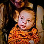 Micah joined the competition — help win amazing prizes! adult, baby, black_top, bonding, cute, face, family, hands, holding, indoor, infant, long_hair, looking_up, orange_clothing, person, portrait, pumpkin_pattern, smile, tattoos, warm_lighting