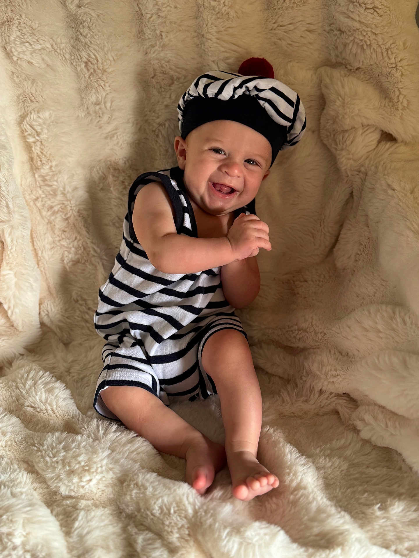 Nolhan a rejoint le concours — aidez-le/la à gagner de superbes lots ! baby, child, smiling, striped_clothing, hat, barefoot, sitting, fluffy_blanket, cozy, happy, portrait, indoor, cute, infant, person, soft_texture, comfortable, playful, young, bright