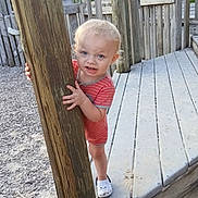 A.j. joined the competition — help win amazing prizes! toddler, child, playground, wooden_post, red_striped_clothing, white_shoes, outdoor, daylight, fence, wood, gravel, curious, peeking, young_child, person, smiling, standing, nature, summer, casual
