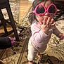 Brooklyn is registered to the contest to win money with this photo: toddler, child, indoor, sunglasses, pink, heart_shaped, barefoot, carpet, rug, furniture, hand, motion_blur, person, home, floor, long_hair, playful, cute, shirt, pants