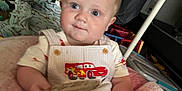 Weston joined the competition — help win amazing prizes! baby, child, infant, blue_eyes, overalls, car_print, pink_cushion, toys, indoor, play_area, smile, face, person, clothing, baby_gear, seat, cute, young_child, comfortable, home