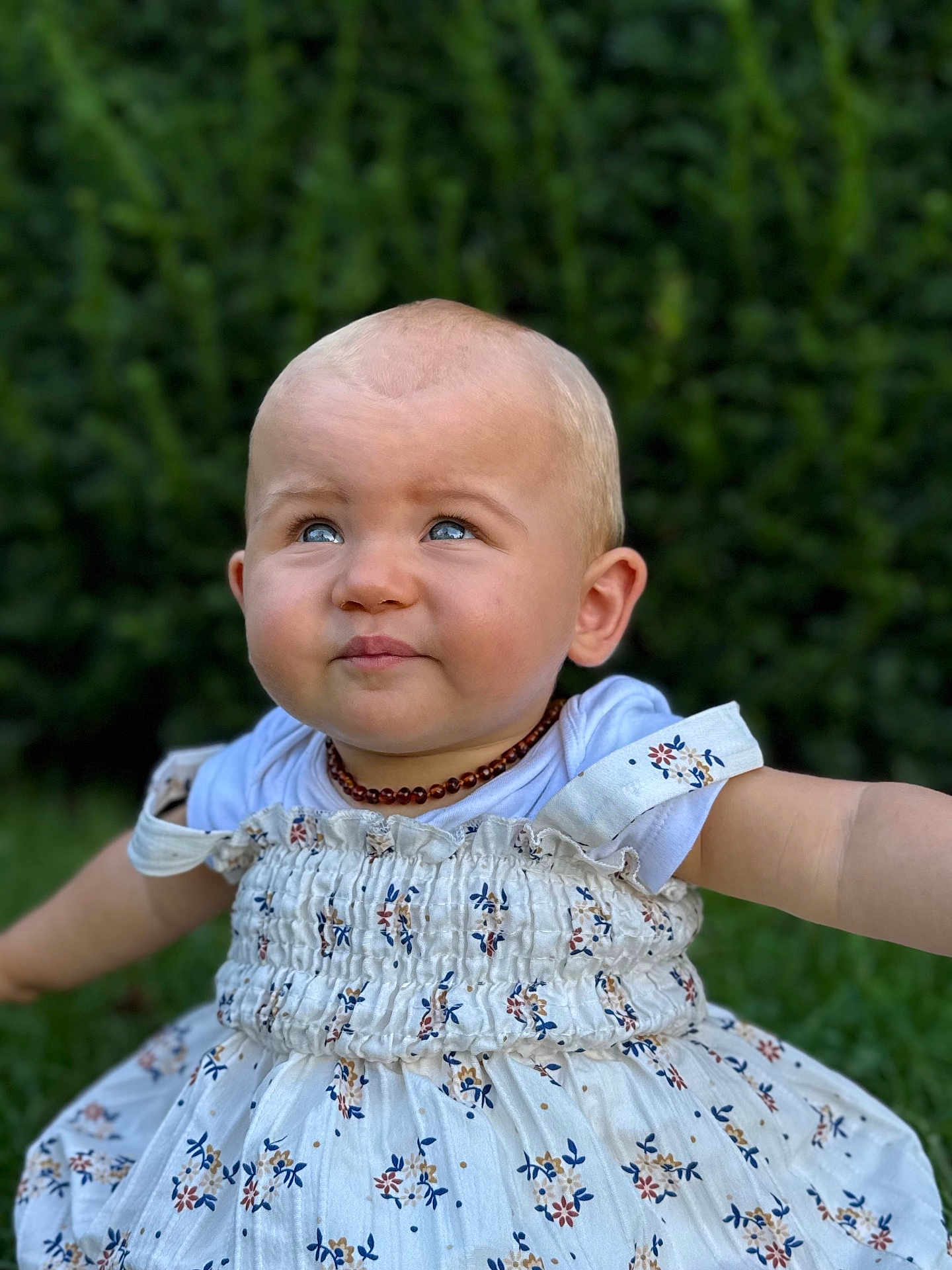Isalya a rejoint le concours — aidez-le/la à gagner de superbes lots ! baby, child, blue_eyes, dress, floral_pattern, outdoor, greenery, grass, smiling, cute, portrait, infant, person, nature, summer, happy, young_child, closeup, head, necklace