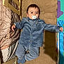 baby, child, pacifier, blue_clothing, blanket, cushion, bed, wooden_frame, play_mat, indoor, infant, cozy, sleepwear, smiling, person, cute, relaxed, soft_texture, lying_down, young