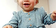 Zaina participe au concours pour gagner de l'argent avec cette photo : toddler, child, smiling, curly_hair, blue_dress, indoor, person, happy, hand, face, buttoned_dress, patterned_clothing, cute, young_child, skin, baby, portrait, sitting, supporting_hand, light