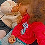 Zaina a rejoint le concours — aidez-le/la à gagner de superbes lots ! child, toddler, couch, clothing, red_sweatshirt, white_jacket, jeans, snack, food, curly_hair, interaction, affection, indoors, cute, playing, happy, sitting, friendship, cozy, casual