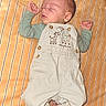 baby, newborn, sleeping, infant, portrait, one_month_old, striped_blanket, overalls, green_shirt, wooden_sign, milestone, lying_down, peaceful, indoors, close_up, face, clothing, baby_photography, resting, cute