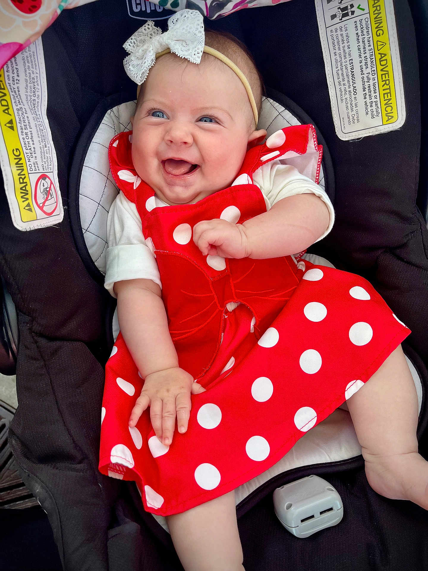 Emma is registered to the contest to win money with this photo: baby, smiling, red_dress, polka_dots, headband, car_seat, infant, happy, child, cute, white_bow, clothing, seat_belt_warning, indoor, person, portrait, baby_girl, cheerful, hand, legs