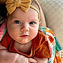 Emma is registered to the contest to win money with this photo: baby, infant, child, face, blue_eyes, headband, bow, orange_shirt, blanket, colorful, pattern, arms, skin, cute, portrait, closeup, indoors, person, smile, young