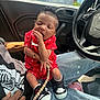 baby, infant, child, person, sitting, car_interior, steering_wheel, clothing, sneakers, nike, pacifier, red_outfit, hand, jeans, sleeping, cute, indoor, window, sunlight, bracelet