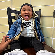 Chōzyn joined the competition — help win amazing prizes! black_beanie, casual_wear, chair, child, cute, denim_jacket, fashion, hand, happy, indoor, nike_shirt, person, playful, portrait, seated, smiling, toddler, tongue_out, white_sneakers, wooden_table