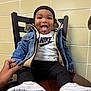 black_beanie, casual_wear, chair, child, cute, denim_jacket, fashion, hand, happy, indoor, nike_shirt, person, playful, portrait, seated, smiling, toddler, tongue_out, white_sneakers, wooden_table