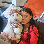 Jeter is registered to the contest to win money with this photo: girl, dog, white_dog, hat, scarf, indoor, living_room, couch, stairs, cushion, red_shirt, long_hair, pet, smiling, holding, cute, cozy, portrait, home, warm