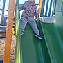 Misael is registered to the contest to win money with this photo: child, slide, playground, outdoor, daylight, clothing, shirt, pants, shoes, handrail, woodchips, metal, plastic, play, recreation, young, person, fun, activity, park