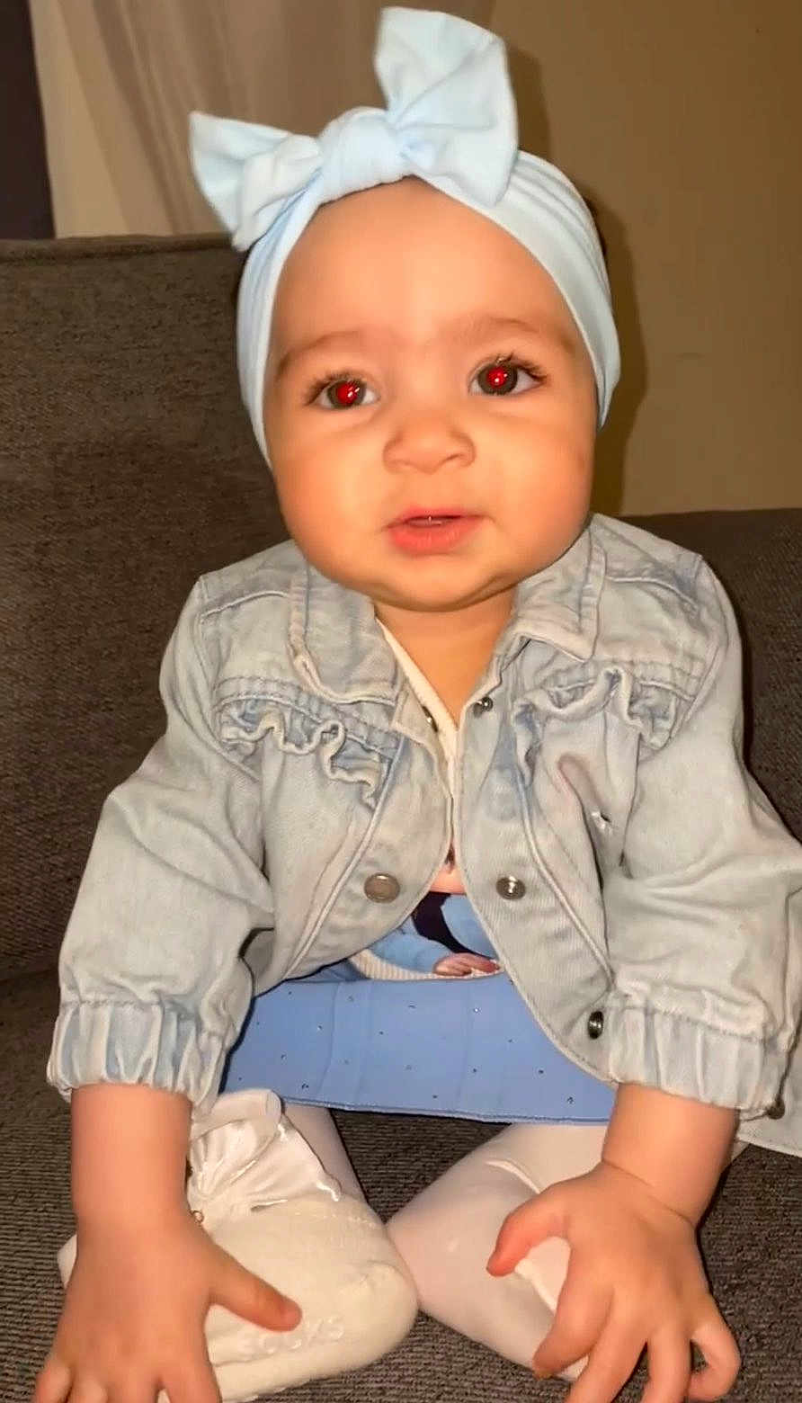 Naïsmèe a rejoint le concours — aidez-le/la à gagner de superbes lots ! toddler, baby, child, denim_jacket, headband, bow, red_eye, sitting, couch, indoors, white_shoes, white_tights, curious, portrait, person, young_child, flash, casual_clothing, face, hand