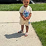 Nuri is registered to the contest to win money with this photo: child, toddler, smiling, outdoor, sidewalk, grass, summer_clothing, sandals, shorts, tshirt, cartoon_character, cute, happy, hair_buns, sunny, shadow, playful, person, portrait, daytime