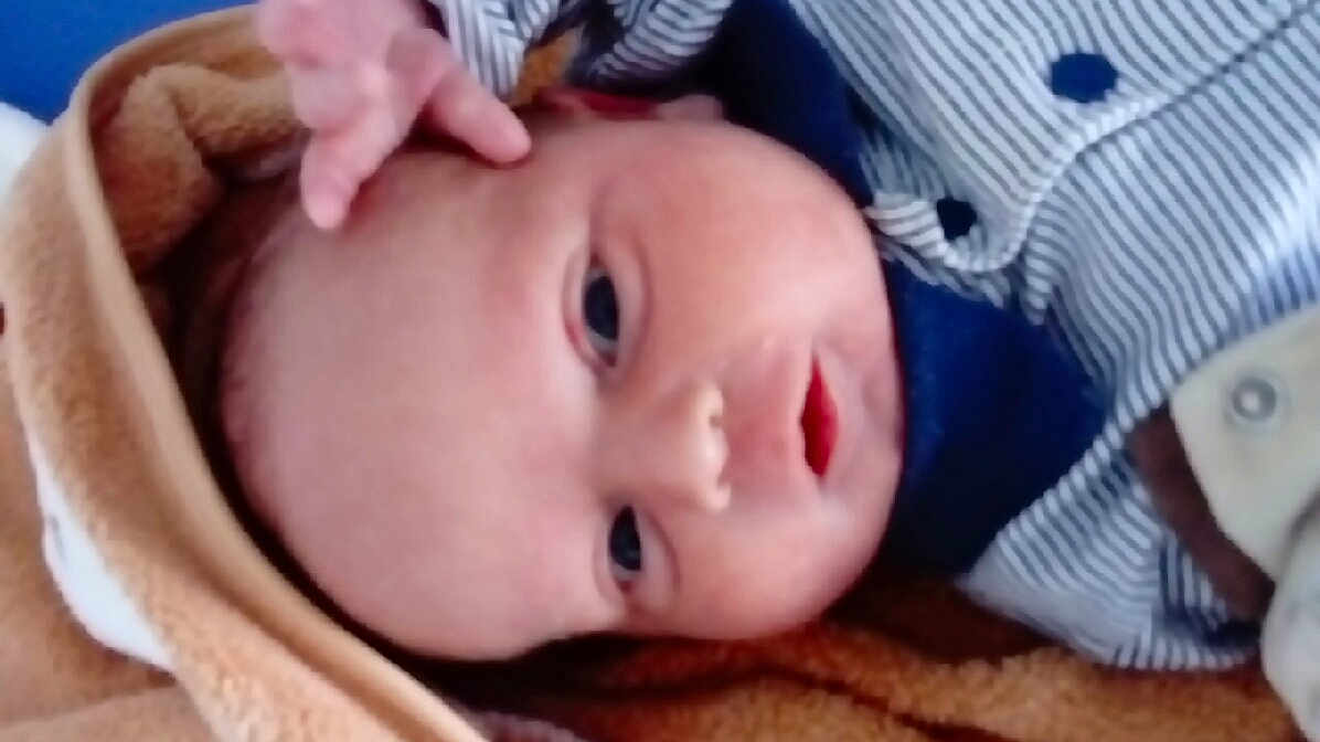 Alexandre participe au concours pour gagner de l'argent avec cette photo : baby, infant, face, hand, blanket, clothing, striped, button, lying_down, closeup, curious, young_child, skin, head, eyes, mouth, soft_texture, indoors, portrait, newborn