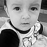 baby, black_and_white, child, close_up, clothing, cushion, eyes, face, home, indoors, looking_at_camera, patterned_fabric, person, photography, pillow, portrait, serious, sitting, t_shirt, toddler