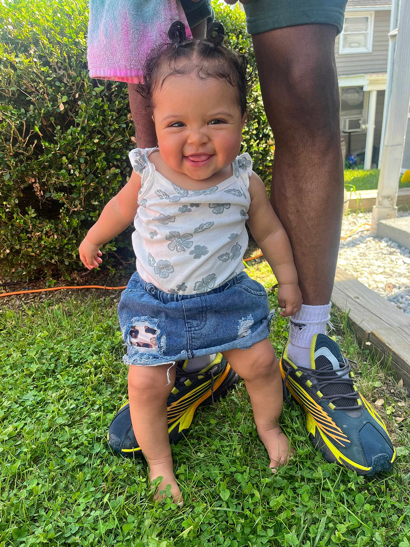 Myyahna is registered to the contest to win money with this photo: toddler, child, baby, grass, smiling, outdoor, denim_skirt, white_top, pigtails, barefoot, adult_legs, shoes, socks, greenery, sunlight, backyard, happy, cute, person, nature