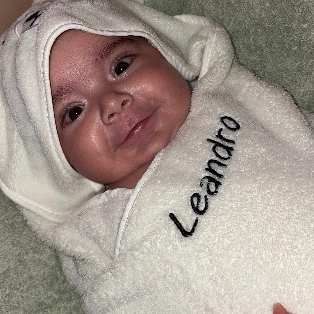 Léandro participe au concours pour gagner de l'argent avec cette photo : baby, towel, hooded_towel, smile, face, infant, wrapped, hand, embroidery, soft_texture, blanket, cozy, cute, child, indoors, person, skin, nail, fingernail, comfort
