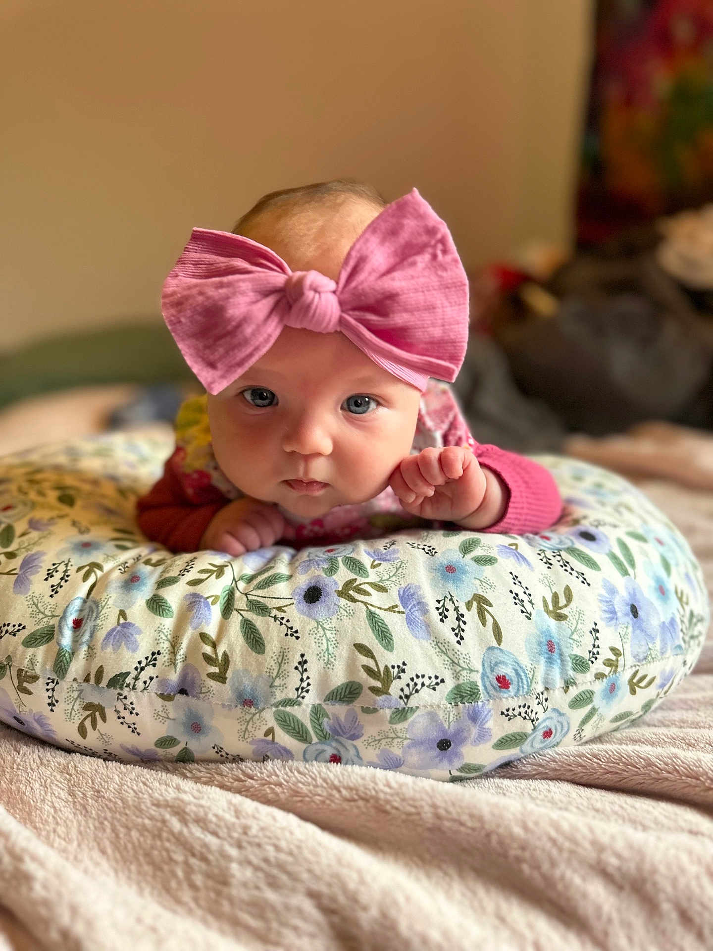 Vienna is registered to the contest to win money with this photo: baby, infant, pink_bow, headband, floral_cushion, blanket, blue_eyes, cute, portrait, indoors, soft_focus, child, newborn, toddler, close_up, sleeping_area, comfort, soft_texture, crawling, hand