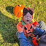 Vienna is registered to the contest to win money with this photo: autumn, baby, black_bow, child, costume, cute, fall, grass, hands, headwear, holding, orange, outdoor, person, pumpkin, shadow, socks, striped_pants, sunlight, yawning