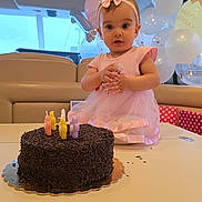 Flore a rejoint le concours — aidez-le/la à gagner de superbes lots ! child, baby, birthday, cake, candles, pink_dress, bow, balloons, party, celebration, indoor, table, chocolate, sprinkles, face, person, happy, cute, smile, event