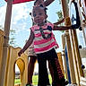 Genesis is registered to the contest to win money with this photo: child, toddler, playground, pacifier, outdoor, play_equipment, person, clothing, sky, daylight, sandals, shorts, hair_buns, grass, handrail, platform, happy, fun, summer, park