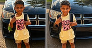 Kamari Jaxyn joined the competition — help win amazing prizes! child, boy, backpack, yellow_shirt, pink_text, black_car, sneakers, outdoor, daylight, standing, smiling, shorts, street, vehicle, reflection, casual_clothing, portrait, happy, person, urban