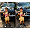 child, boy, backpack, yellow_shirt, pink_text, black_car, sneakers, outdoor, daylight, standing, smiling, shorts, street, vehicle, reflection, casual_clothing, portrait, happy, person, urban