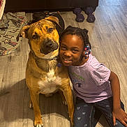 Nacho is registered to the contest to win money with this photo: animal, beads, blanket, casual_clothing, child, collar, couch, dog, dumbbells, floor, friendship, girl, happy, head_tilt, indoor, kneeling, pet, portrait, smiling, wooden_floor