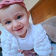 Camille participe au concours pour gagner de l'argent avec cette photo : baby, child, smiling, crawling, headband, pink_bow, white_clothing, long_sleeves, indoor, face, cute, happy, closeup, person, infant, young_child, bright_eyes, soft_texture, warm_lighting, portrait