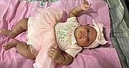 Deasia is registered to the contest to win money with this photo: baby, baby_clothing, bed, bow, child, dress, eyes, face, happy, headband, indoors, infant, looking_at_camera, lying_down, nursery, pastel, photograph, pink_blanket, portrait, textile