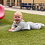 baby, casual_clothing, child, crawling, daylight, face, fun, grass, green, happy, hoodie, infant, nature, outdoor, pants, park, person, playground, red_slide, smile