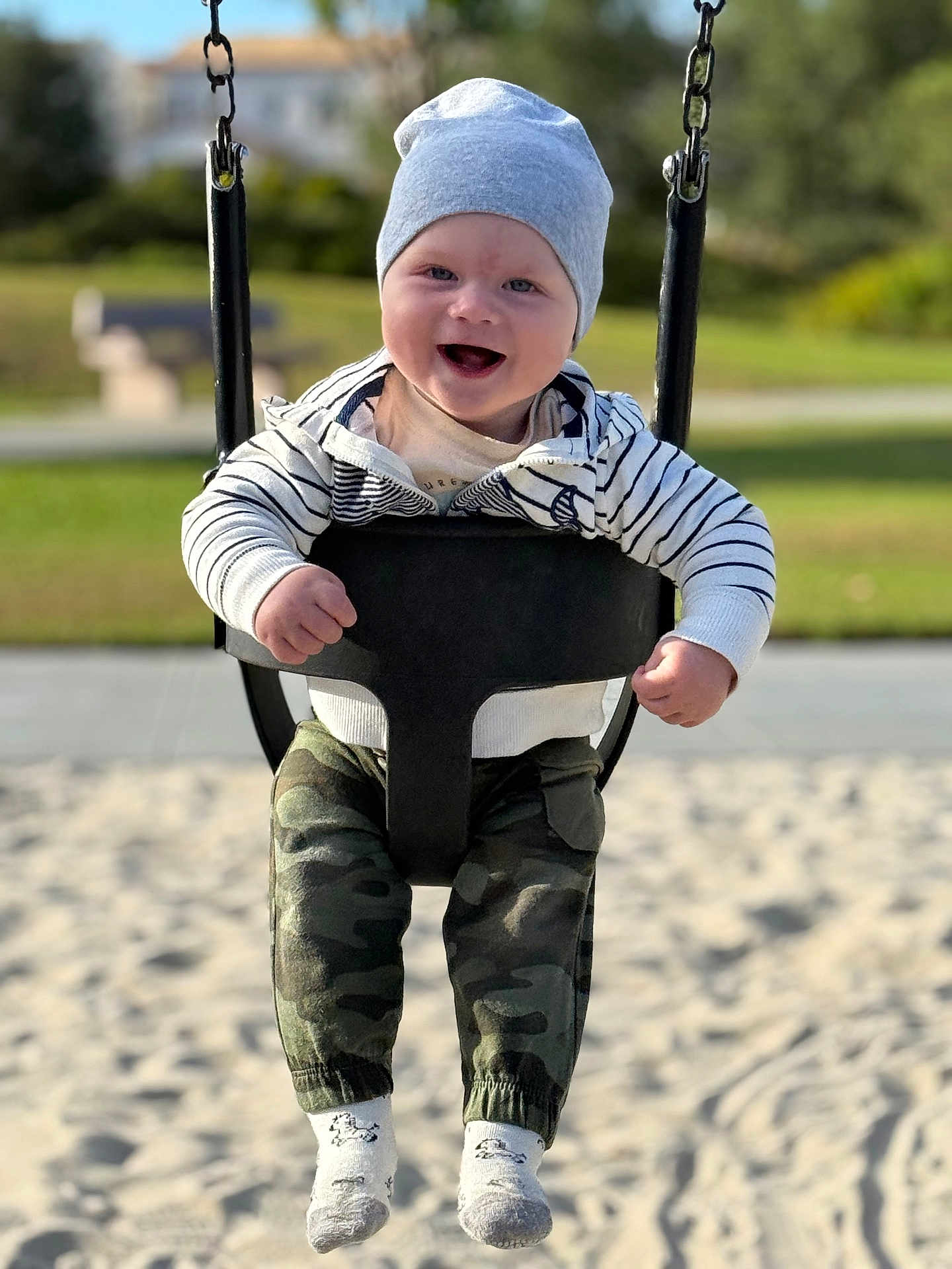 Mark joined the competition — help win amazing prizes! baby, child, swing, playground, hat, smile, happy, outdoor, park, sand, clothing, camo_pants, sock, person, daylight, fun, joy, infant, seat, chains