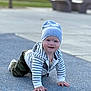 baby, child, crawling, beanie, striped_hoodie, blue_surface, outdoor, playground, park_bench, greenery, happy, smiling, person, casual_clothing, cute, young_child, daylight, playing, fun, headwear