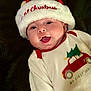 baby, background, celebration, child, christmas_hat, christmas_tree, closeup, cozy, cute, face, festive_clothing, happy, holiday, indoors, infant, onesie, portrait, red_car, smiling, soft_texture