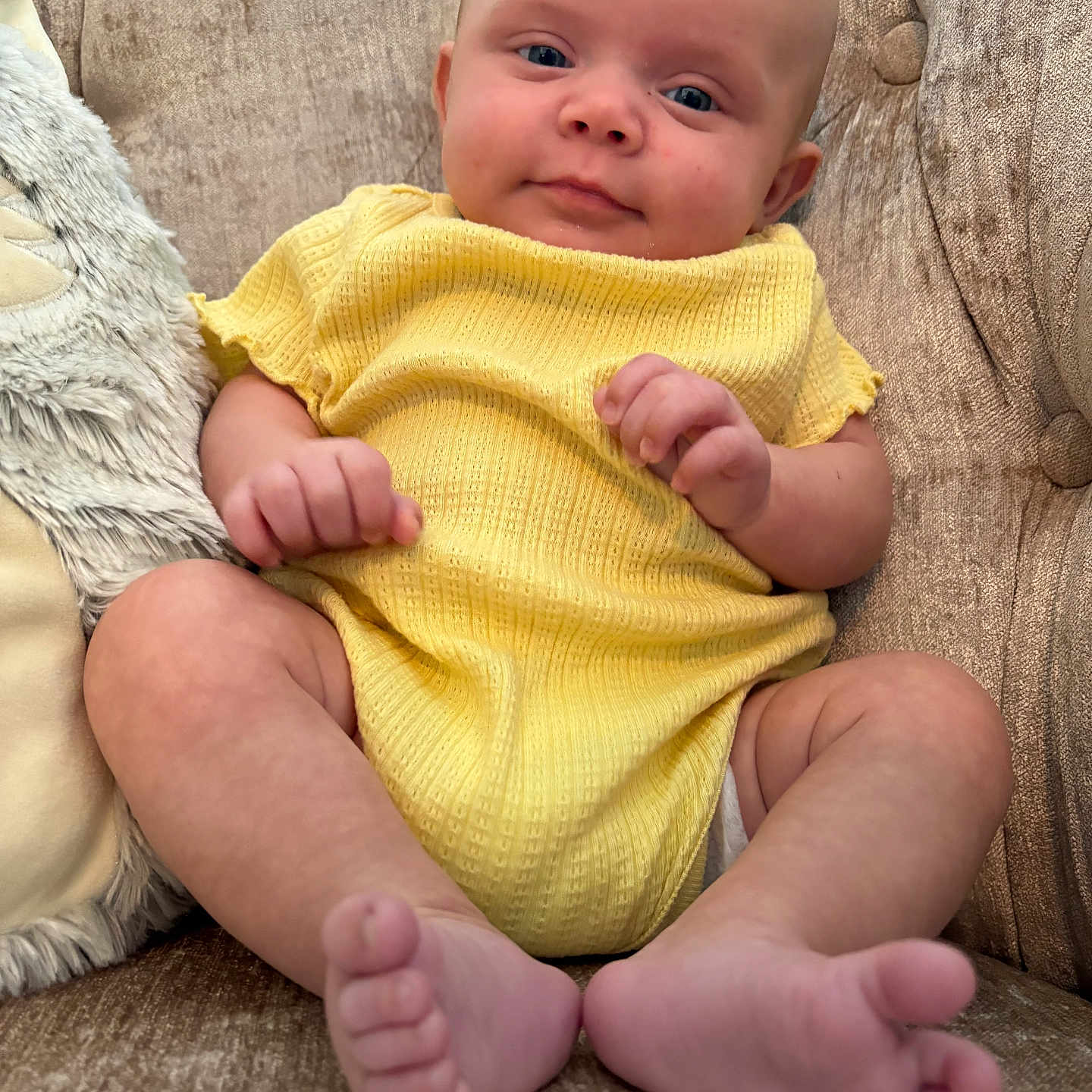 Raylynn joined the competition — help win amazing prizes! baby, barefoot, blue_eyes, child, comfort, couch, cute, face, hands, indoor, infant, plush_pillow, portrait, relaxed, seated, skin, sofa, texture, toes, yellow_clothing