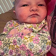 Bailey is registered to the contest to win money with this photo: baby, infant, face, person, blanket, floral_pattern, clothing, indoor, portrait, closeup, curious, wrapped, holding, human, young_child, sitting, soft_lighting, casual, relaxed, home