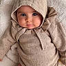 baby, infant, hooded_clothing, knitted_outfit, beige, blanket, soft_texture, cute, portrait, lying_down, face, eyes, pout, cozy, child, warm_clothing, indoors, skin, person, young_child