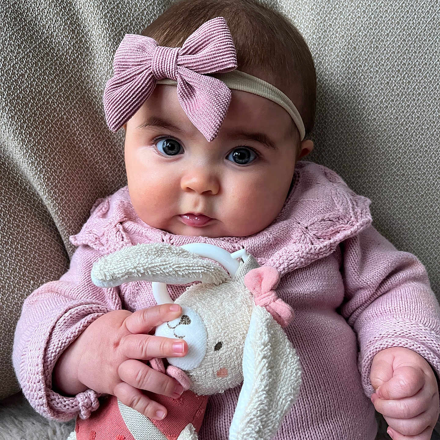 Luz a rejoint le concours — aidez-le/la à gagner de superbes lots ! baby, infant, pink_clothing, headband, bow, plush_toy, bunny, soft_toy, knitwear, cute, child, portrait, indoors, cozy, hand, face, expression, sitting, texture, background