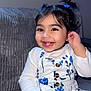 toddler, child, smiling, happy, girl, dress, blue, white, floral_pattern, sitting, couch, indoor, portrait, cute, long_sleeve, buttoned, hair_bow, black_hair, playful, young_child