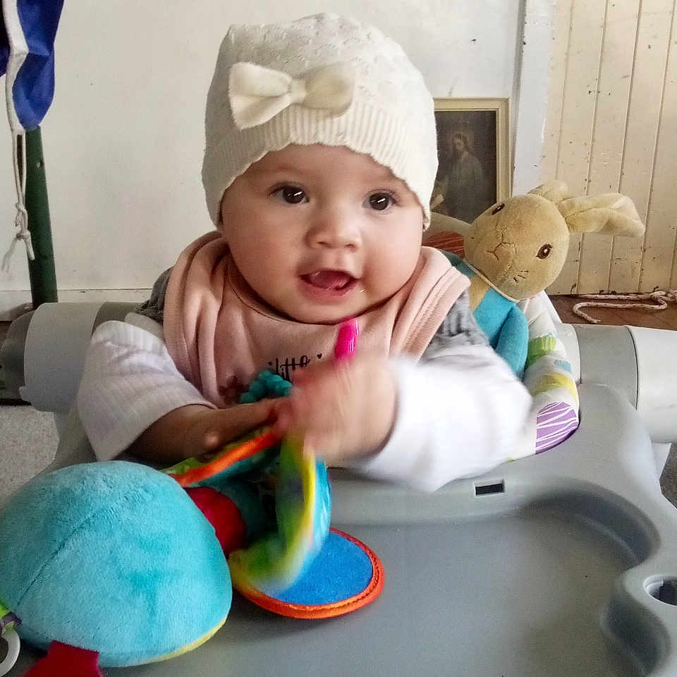 Loren Anakiwa joined the competition — help win amazing prizes! baby, child, clothing, colorful, cute, face, flag, hand, hat, indoor, infant, person, play, plush_bunny, seat, smiling, table, toy, walker, wooden_panel