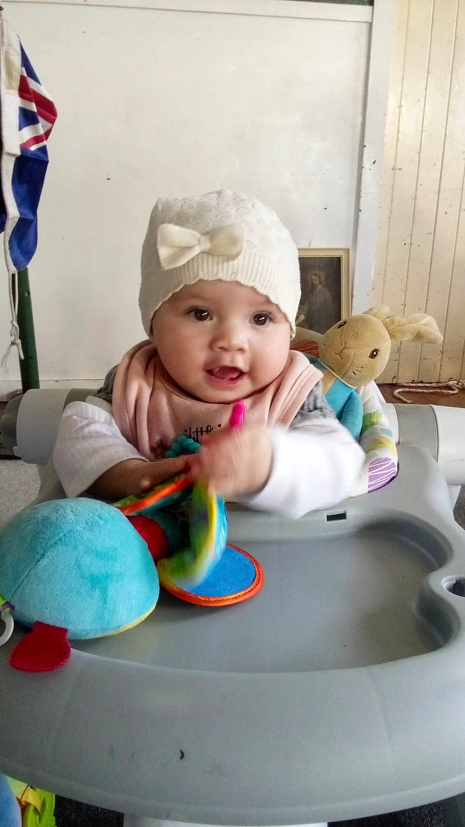 Loren Anakiwa joined the competition — help win amazing prizes! baby, child, walker, toy, plush_bunny, hat, indoor, smiling, colorful, clothing, person, face, hand, flag, wooden_panel, table, seat, infant, play, cute