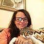 Ollie joined the competition — help win amazing prizes! woman, cat, glasses, smile, indoor, portrait, hand, pet, tabby_cat, couch, blanket, framed_photo, wall, long_hair, ring, casual_clothing, relaxed, home_interior, seated, closeup