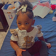 Priya joined the competition — help win amazing prizes! bed, blue_bedspread, bow, child, clutter, cute, flower_emoji, hair_accessory, home, indoor, laundry_basket, motivational_text, pacifier, person, shirt, sitting, socks, teddy_bear, toddler, window