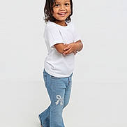 Janessa joined the competition — help win amazing prizes! child, toddler, smiling, portrait, studio, standing, fashion, white_shirt, blue_jeans, casual_clothing, long_hair, crossed_arms, barefoot, full_body, indoor, white_background, happy, young_person, photography, fashion_pose
