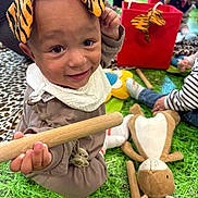 Cookie joined the competition — help win amazing prizes! toddler, child, toy, playmat, stuffed_animal, wooden_stick, ear_headband, smiling, indoor, playroom, colorful, happy, clothing, person, floor, green, baby, cute, kids, playtime