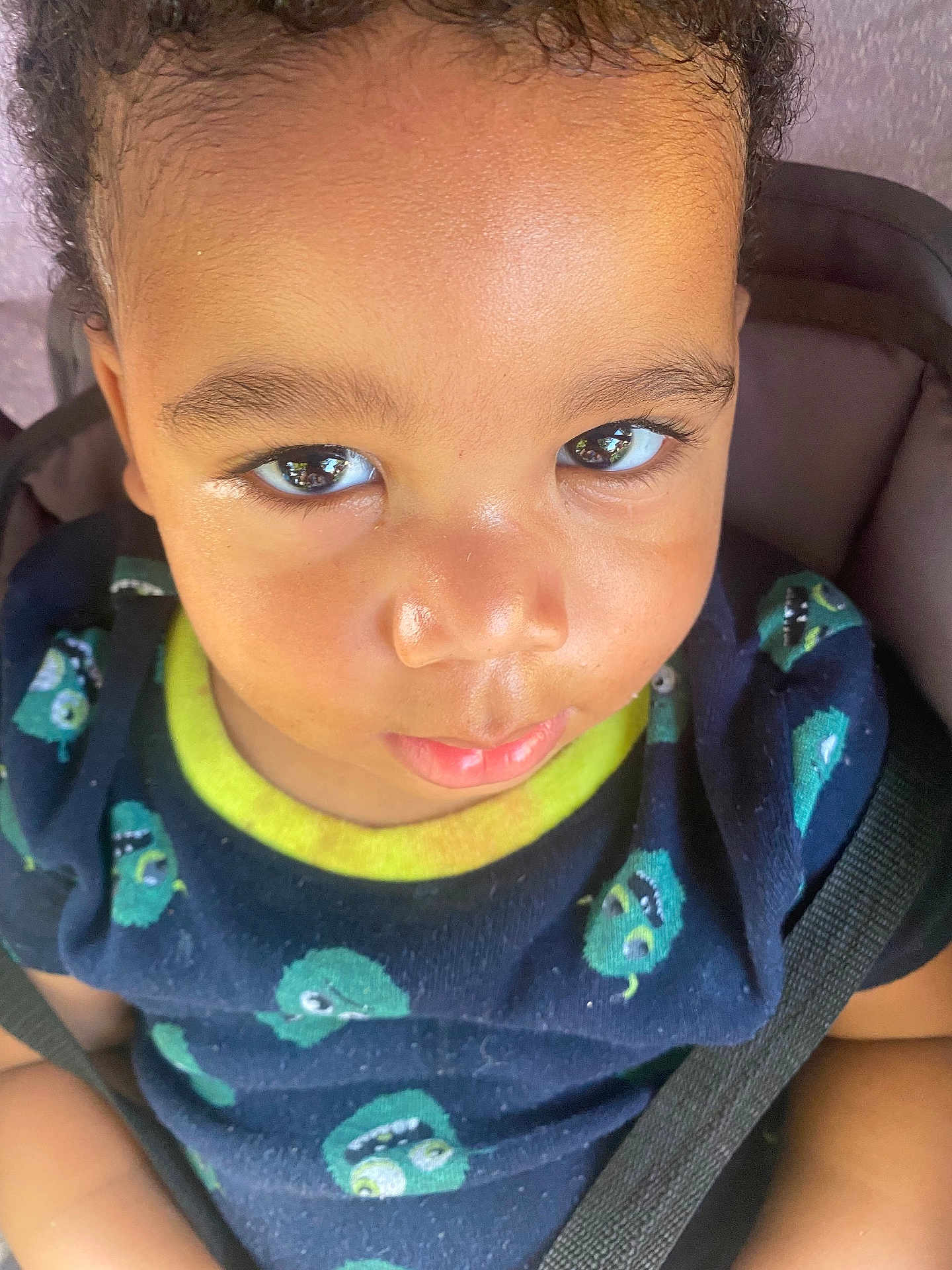 Zion is registered to the contest to win money with this photo: child, toddler, face, eyes, smile, clothing, shirt, seatbelt, car_seat, portrait, indoor, cute, young, baby, person, closeup, expression, curious, sitting, casual