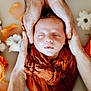 baby, newborn, sleeping, infant, hands, adult_hands, swaddle, milk_bath, flowers, petals, portrait, closeup, skin, cozy, peaceful, studio_photography, indoor, orange_cloth, flower_bath, head